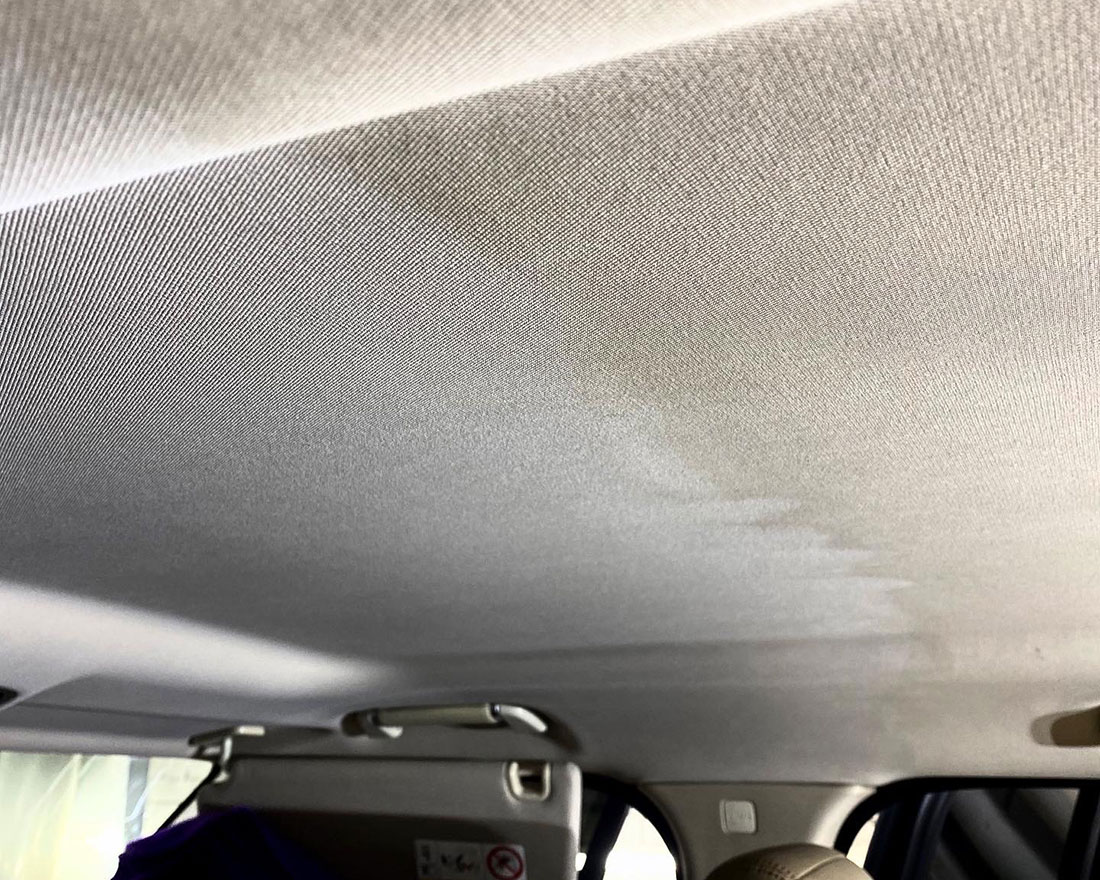 На фото потолок автомобиля в процессе чистки. Левая часть уже чистая и белая, а правая – грязная, бурая.